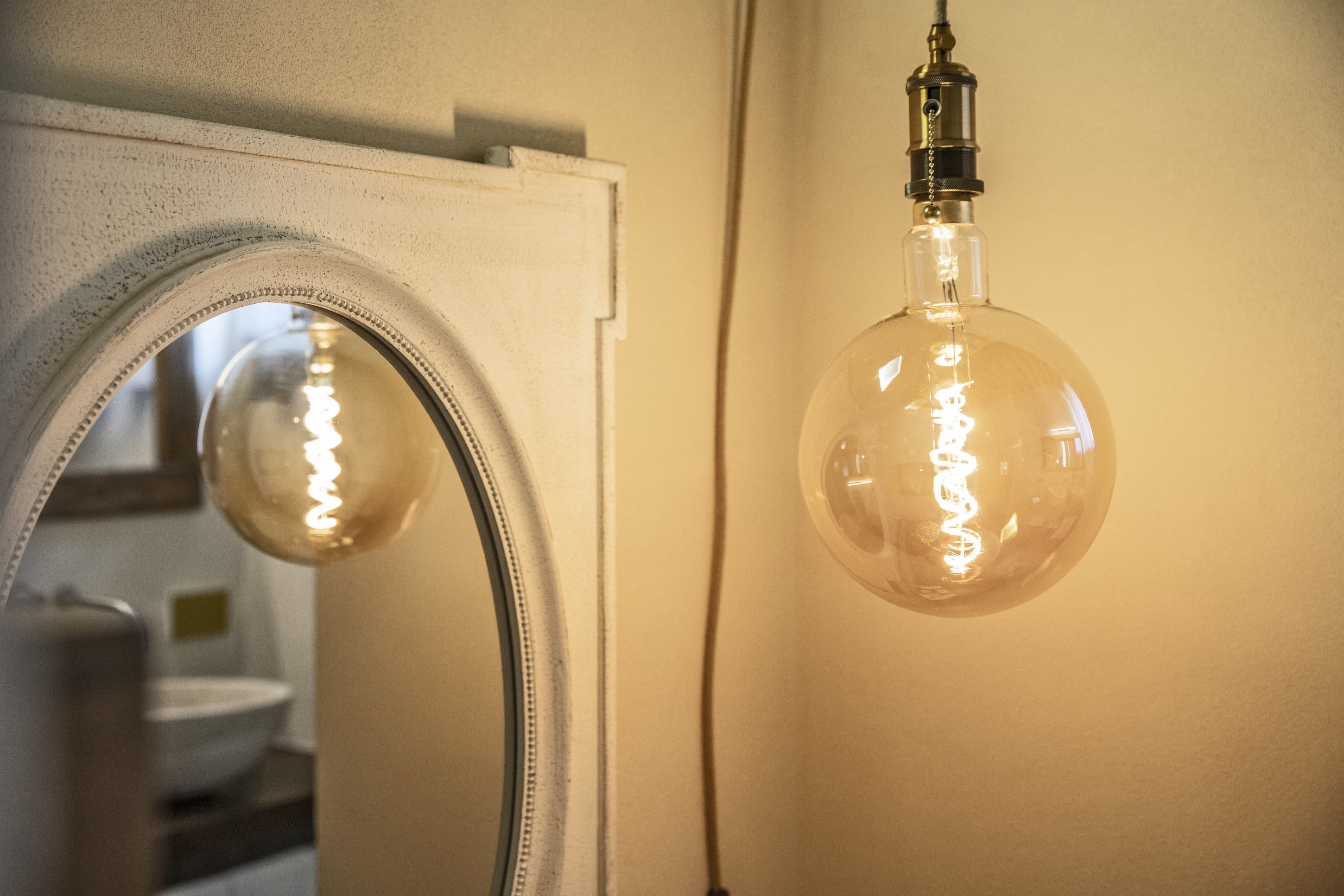 Un bagno con uno specchio, un lampadario e un water.