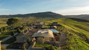 Una villa con piscina, edificios de piedra y vistas al campo circundante.