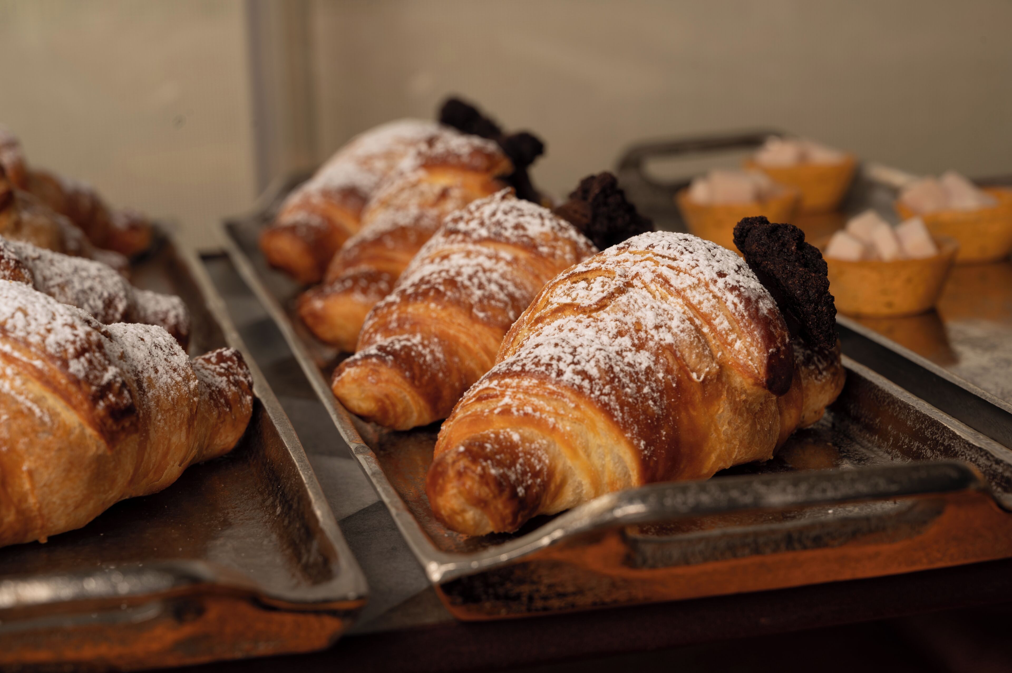 A tray of pastries, including croissants and small tarts, on a wooden surface.