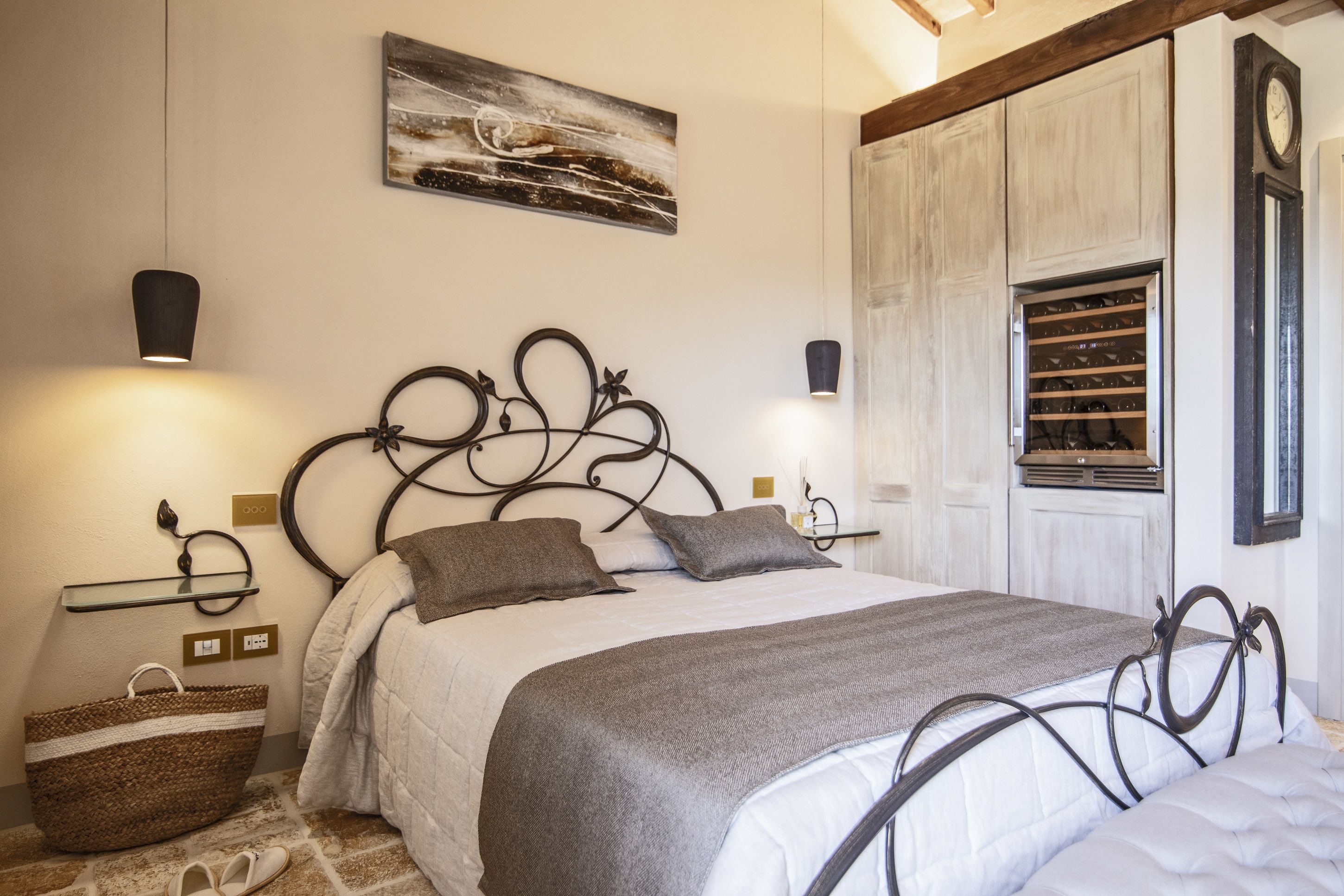 A neatly made bed with a headboard, bedside lamps, and a large woven basket.