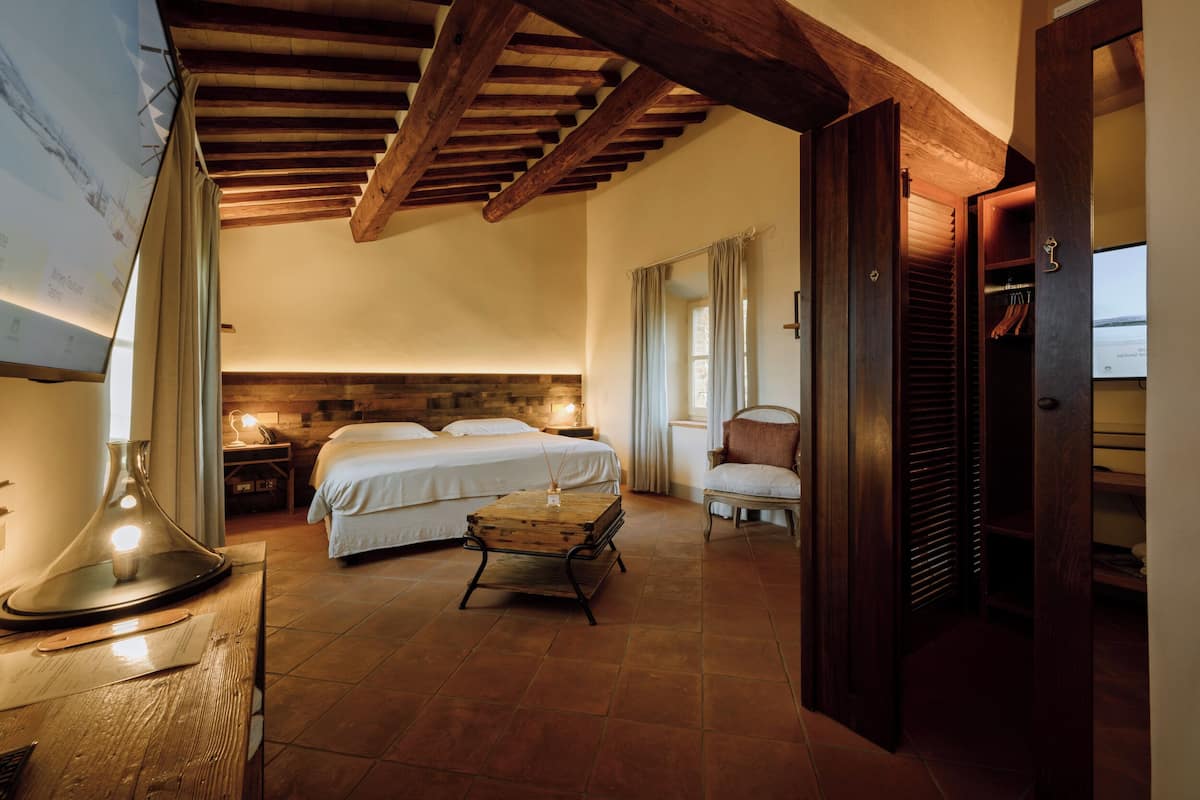 Une chambre à coucher avec un lit, une table de chevet, une lampe et une commode en bois.