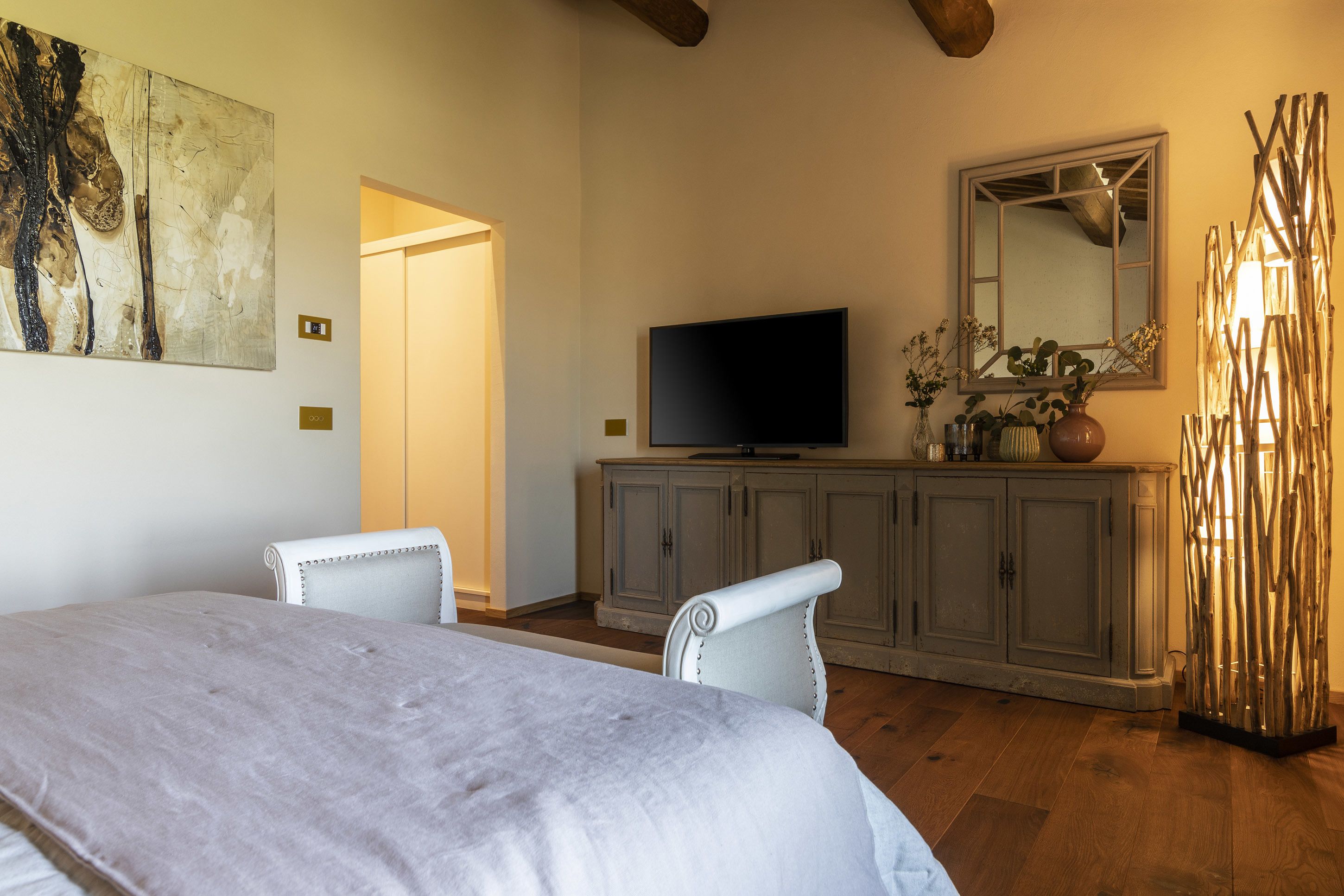 Un dormitorio con cama, televisión, armario y espejo.