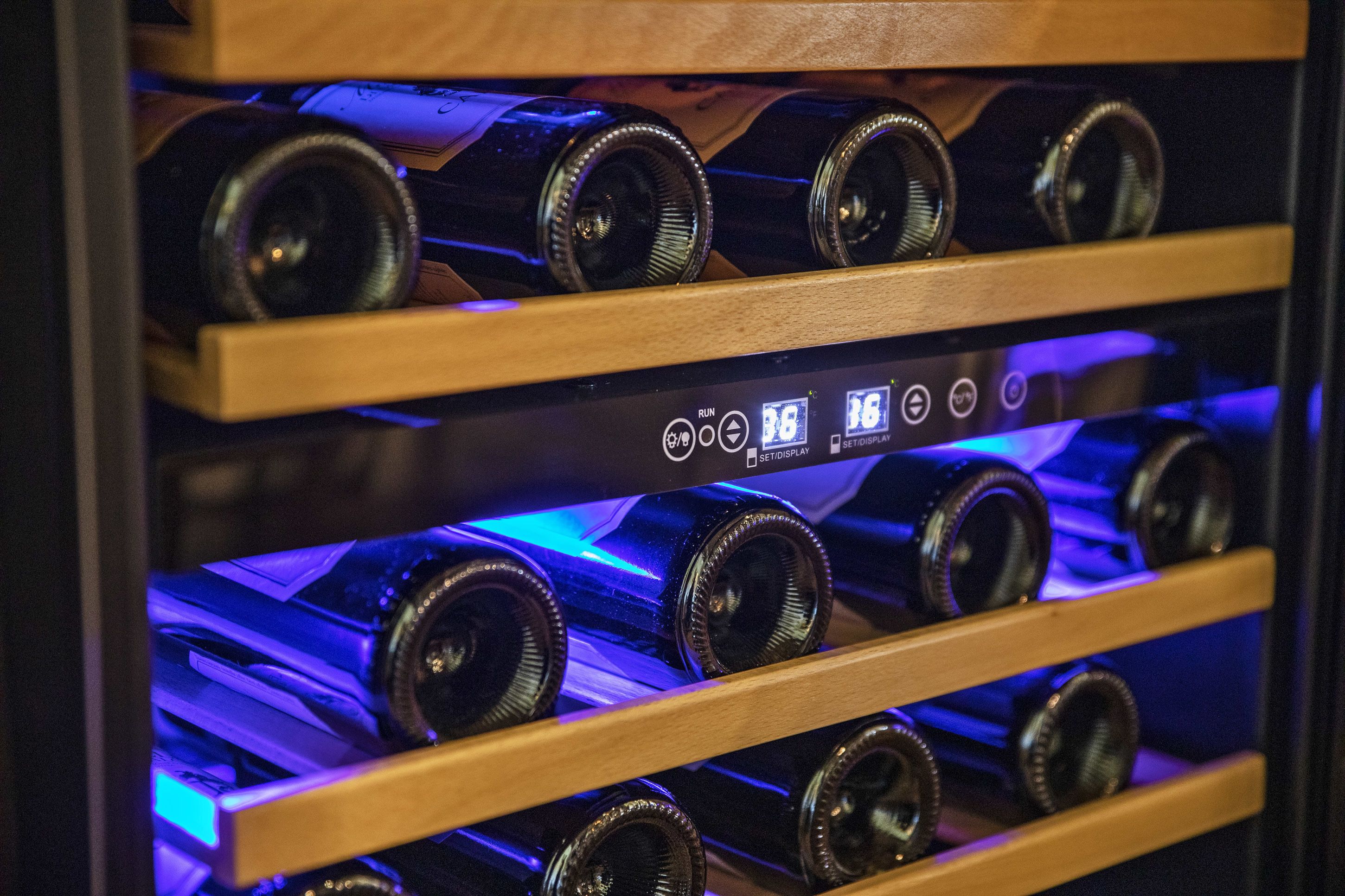 A wine rack with bottles and a control panel with buttons and a display.