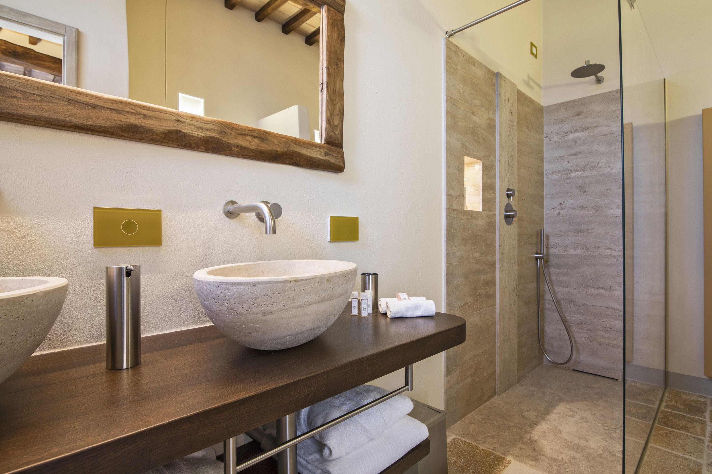 Un bagno con due ampi lavabi, uno specchio, una doccia e un portasciugamani.