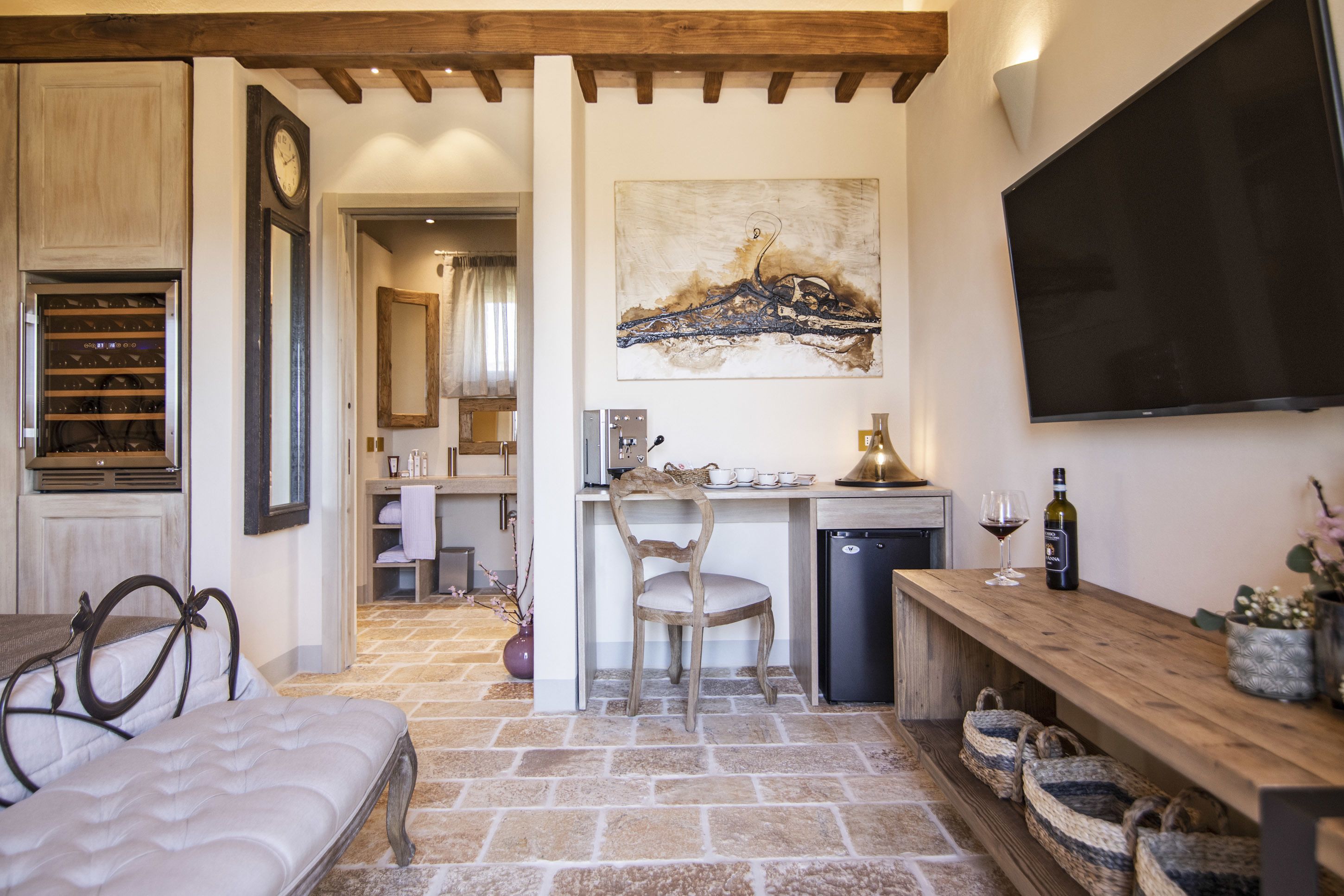Una habitación acogedora con cama, un escritorio de madera, una silla, televisor y un cuadro en la pared.