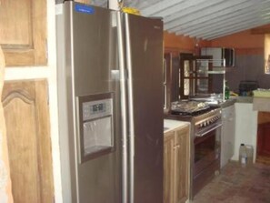 A compact kitchen with a stainless steel refrigerator, a microwave, and a stove. - Provencal farmhouse with large swimming pool in the heart of nature (Le Plan-De-La-Tour)