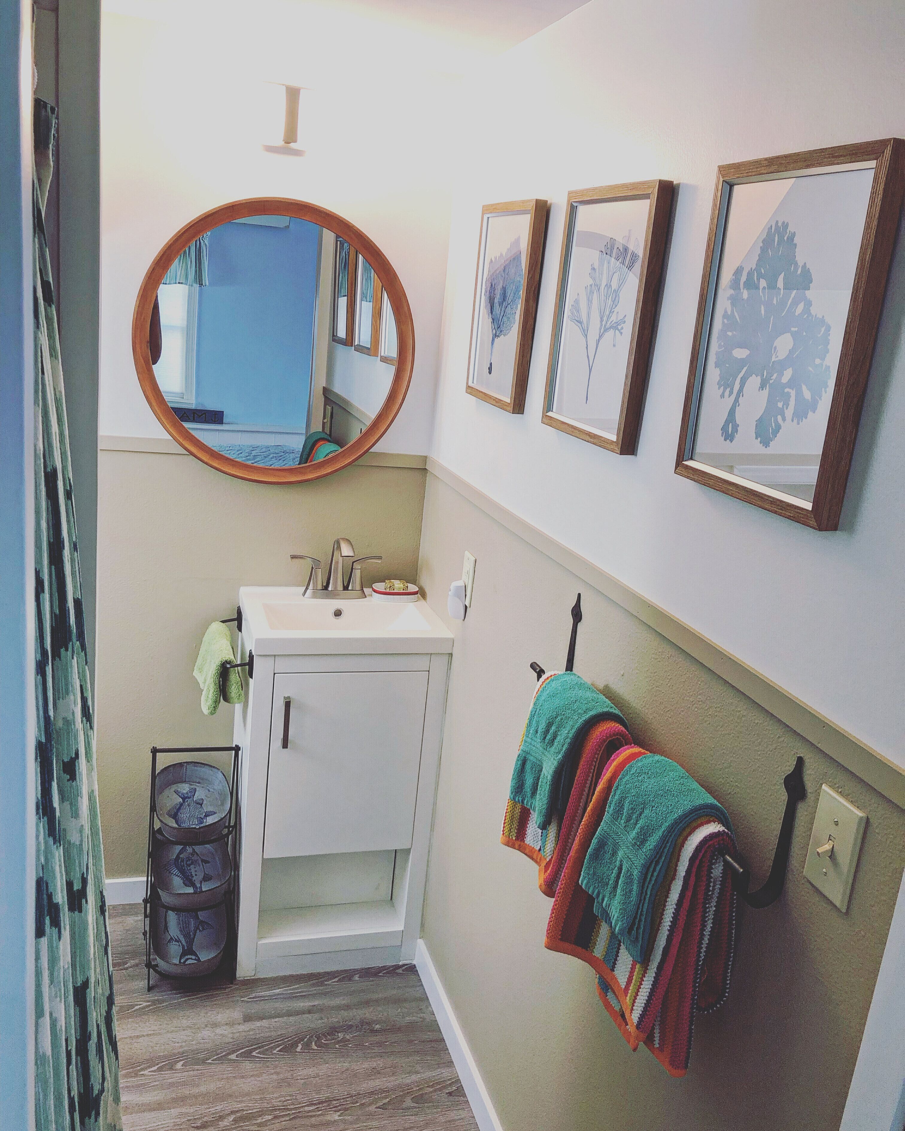 A bathroom with a white sink, a mirror, and framed botanical prints on the wall.