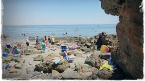 Una playa rocosa con gente y sillas de playa.