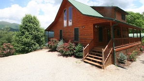 A wooden cabin with a green roof, a porch, and a gravel driveway. - Lakefront 3-bedroom cabin on Fontana Lake with stunning views and a private dock (Robbinsville)