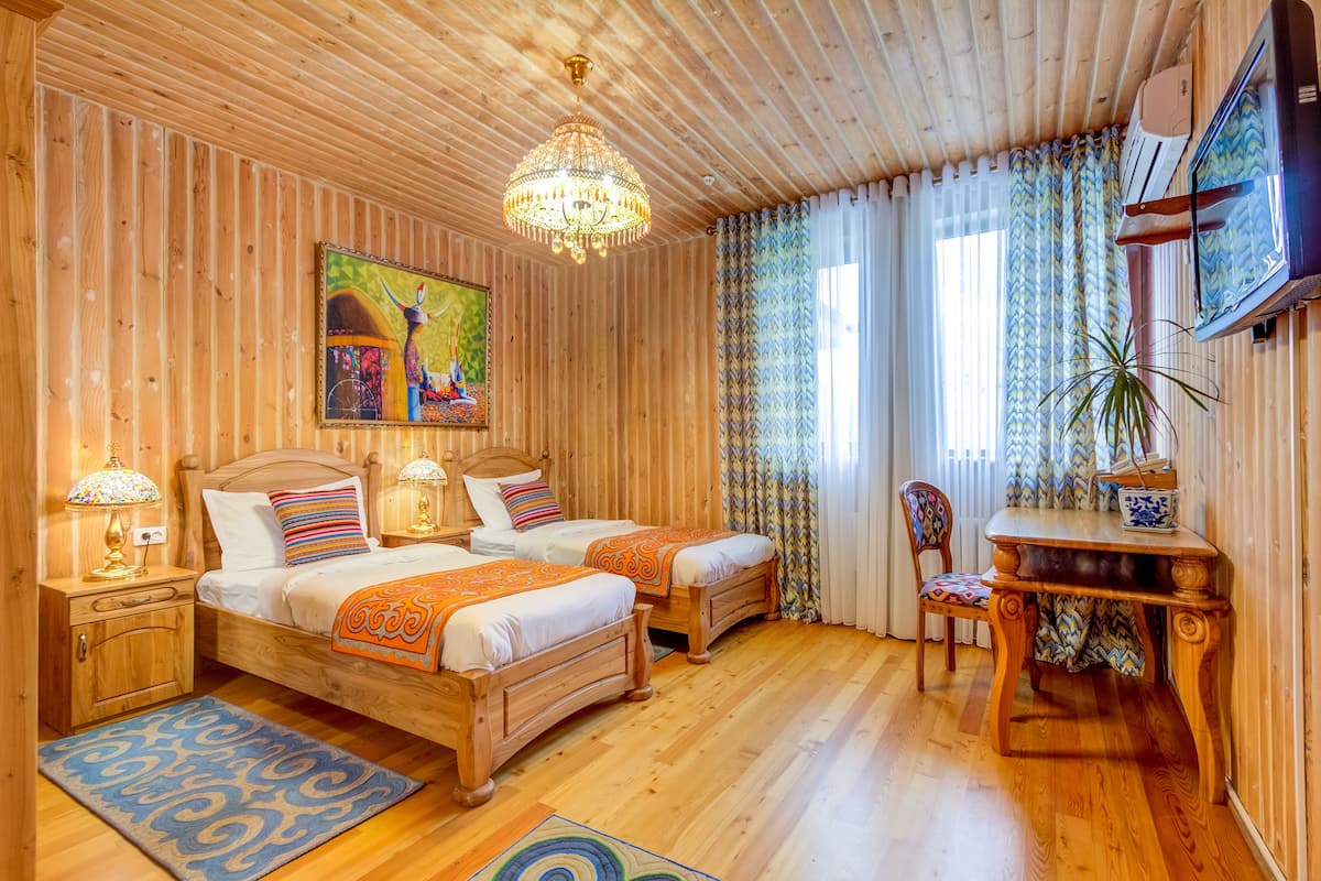Ein Zimmer mit Holzwänden, zwei Betten, einer Kandelaber, einem Gemälde, einem Fernseher und einem Essbereich.
