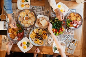 A dining table with various breakfast dishes including pancakes, eggs, and sausages.