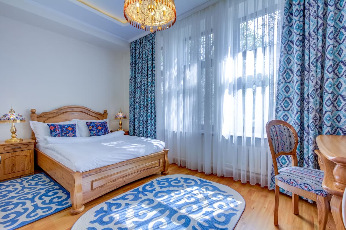 Ein Schlafzimmer mit einem hölzernen Bett, gemusterten Vorhängen und einem Kronleuchter.