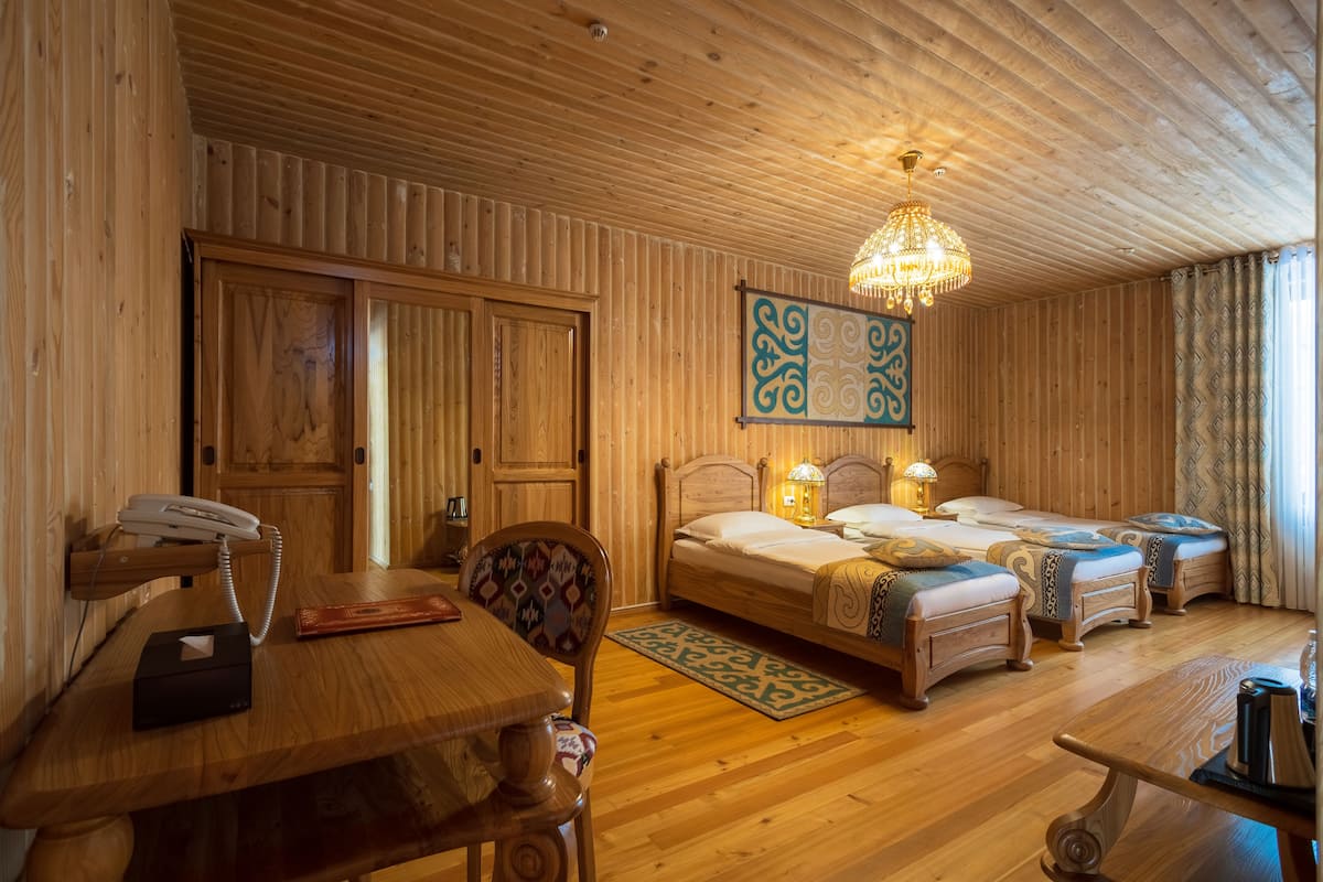 Ein Zimmer mit Holzwandverkleidung, einem Holztisch, einem Telefon, einem Stuhl, einem Bett, einem Nachttisch und einer Pendelleuchte.