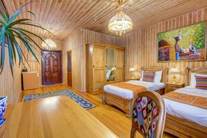 A wooden-paneled room with two beds, a chandelier, and a painting on the wall.
