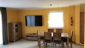 Una sala de estar con televisor, muebles de madera, una ventana y un armario.