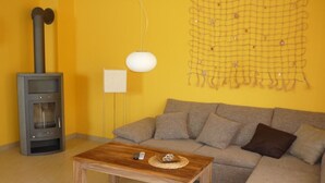 Una sala de estar con sofá, mesa de centro de madera, chimenea y decoración en la pared.