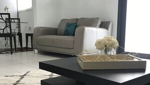 A modern living room with a sofa, coffee table, and decorative vase with flowers.
