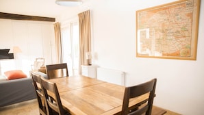 A dining area with a wooden table and chairs, a map on the wall, and a window with curtains. - Le Duplex - Pontaly Farm (BAILLY)