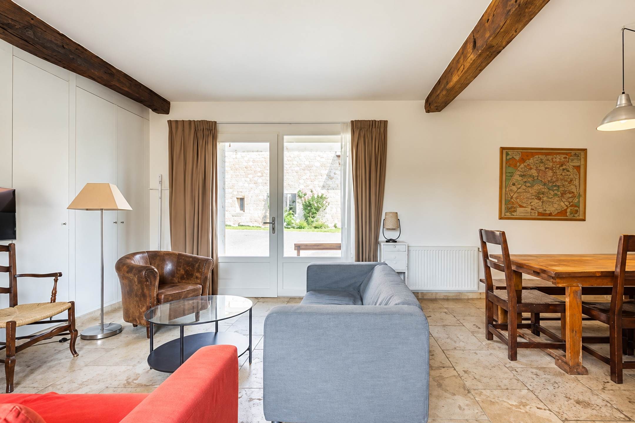 Ein Wohnzimmer mit einer Couch, Sesseln, einem Couchtisch und einem Esstisch mit Stühlen.