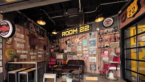 Una habitación con decoración temática de motocicletas, que incluye placas de matrícula en las paredes y un cartel de Harley-Davidson. Hay varias mesas y sillas dispuestas para sentarse.