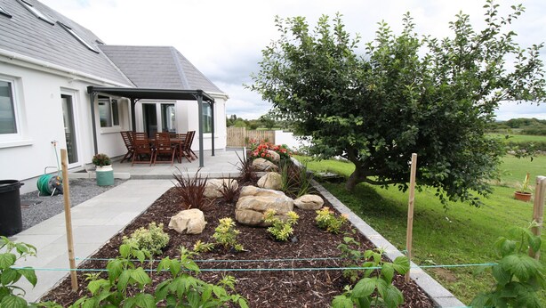 Un jardín con diversas plantas y un patio con mesa y sillas.