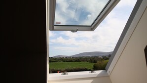 Ventana de tragaluz con vista a un campo verde y colinas lejanas.