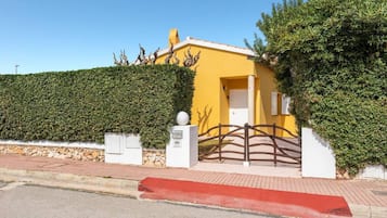 A small, standalone residence with an entrance and a well-manicured hedge.