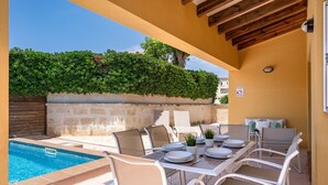 Un espace aménagé au bord de la piscine, comprenant une table à manger, des chaises et une piscine.