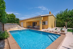 Une piscine avec des chaises longues et un petit bâtiment doté d’un toit en tuiles.
