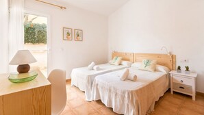 Une chambre d’hôtel avec deux lits, un bureau avec une lampe, une chaise et une table de chevet avec une plante.