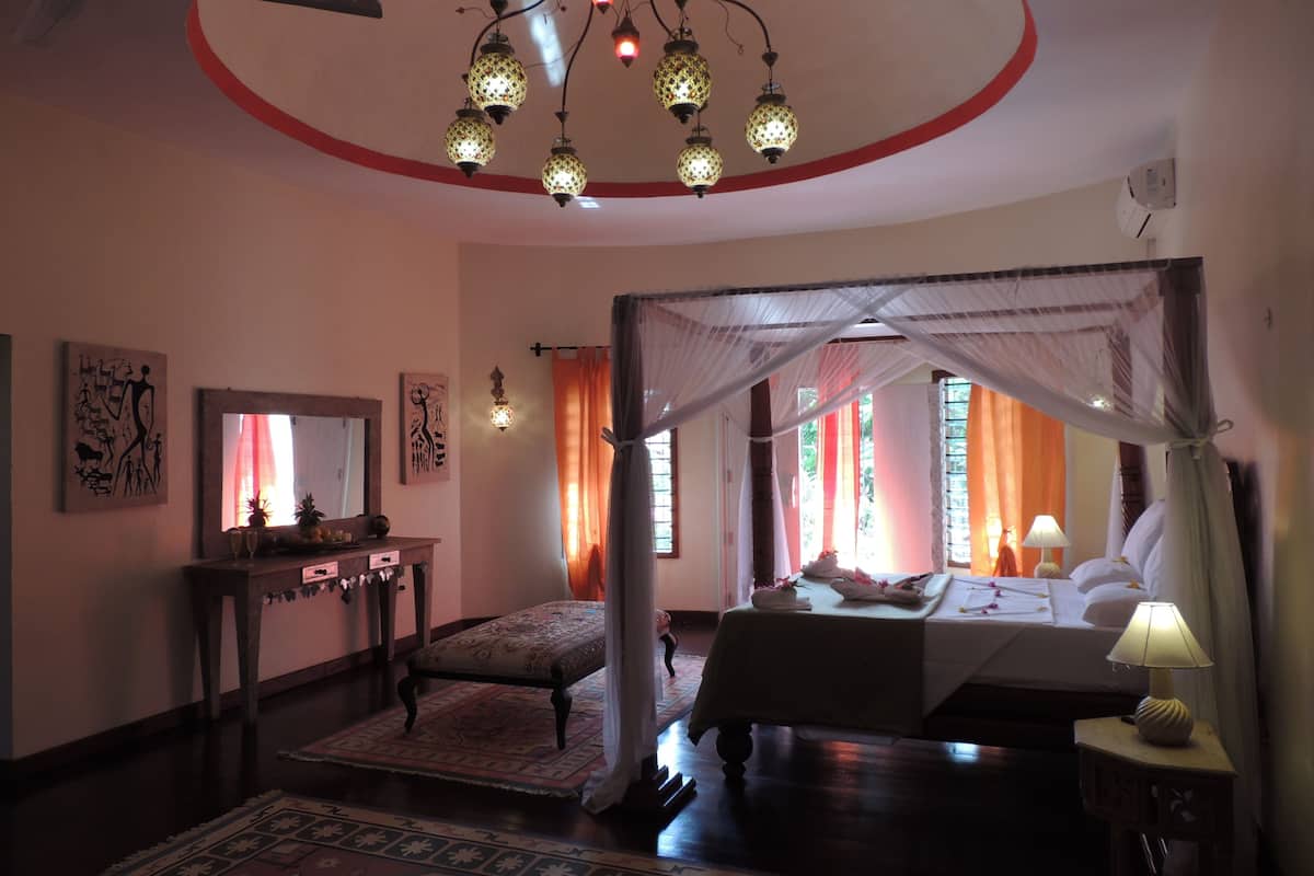A bedroom with a canopy bed, a bedside table with a lamp, and a nightstand.