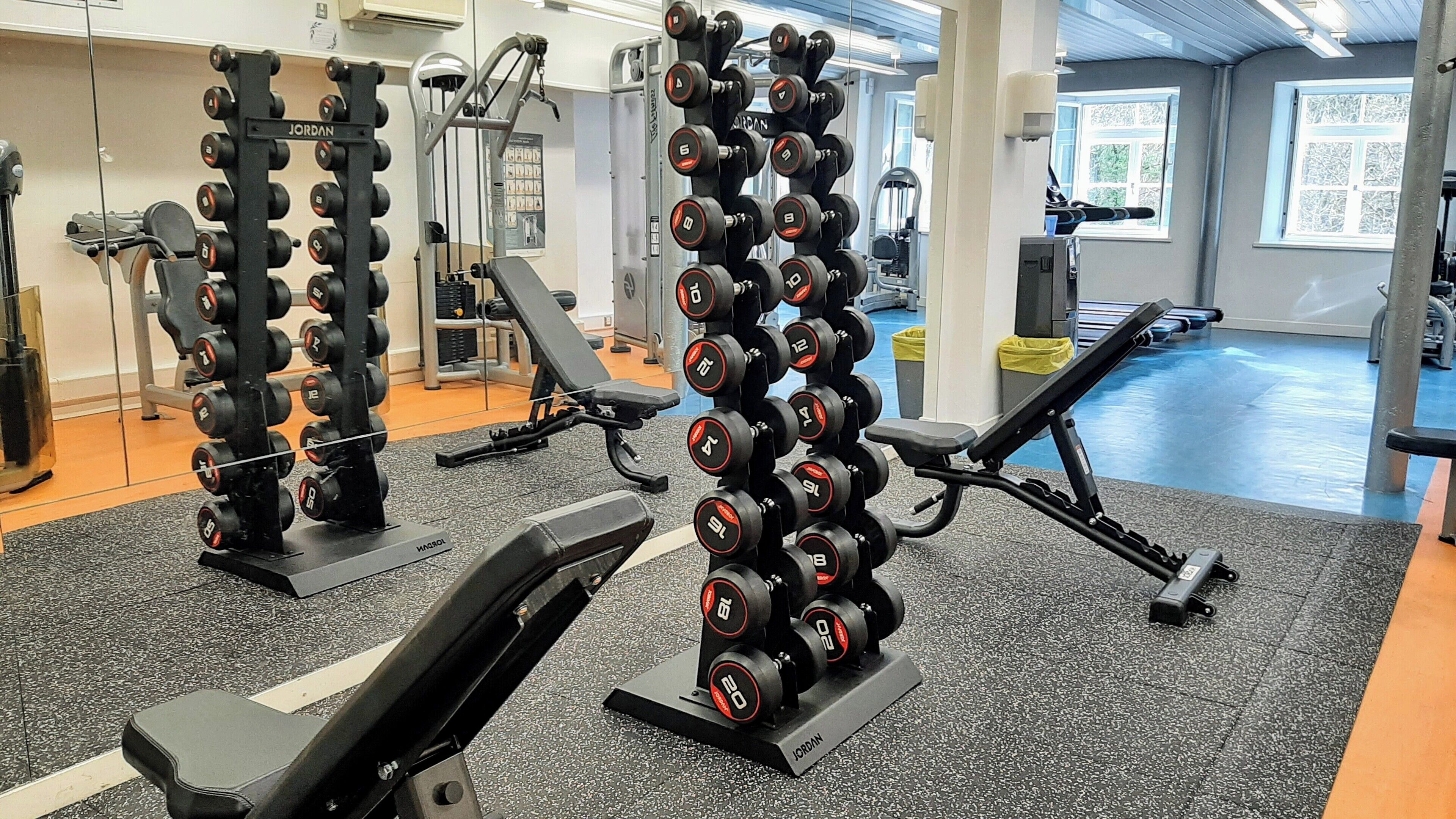 Une salle de sport équipée de matériel de musculation, notamment des haltères et des bancs.