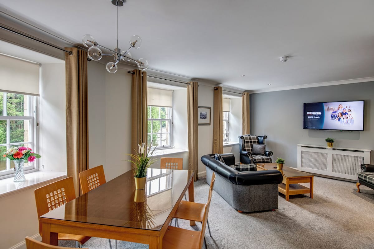 Una sala de estar moderna con comedor, ventanas amplias, un televisor de pantalla plana y chimenea.