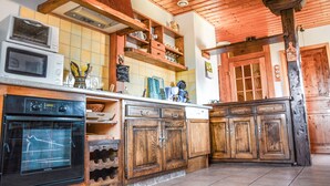 Eine Küche mit Holzausstattung, einem eingebauten Backofen und einer Pendelleuchte.