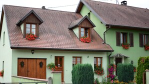 Ein zweistöckiges Haus mit einem steilen Satteldach, Holztüren und Fenstern mit Blumenkästen.