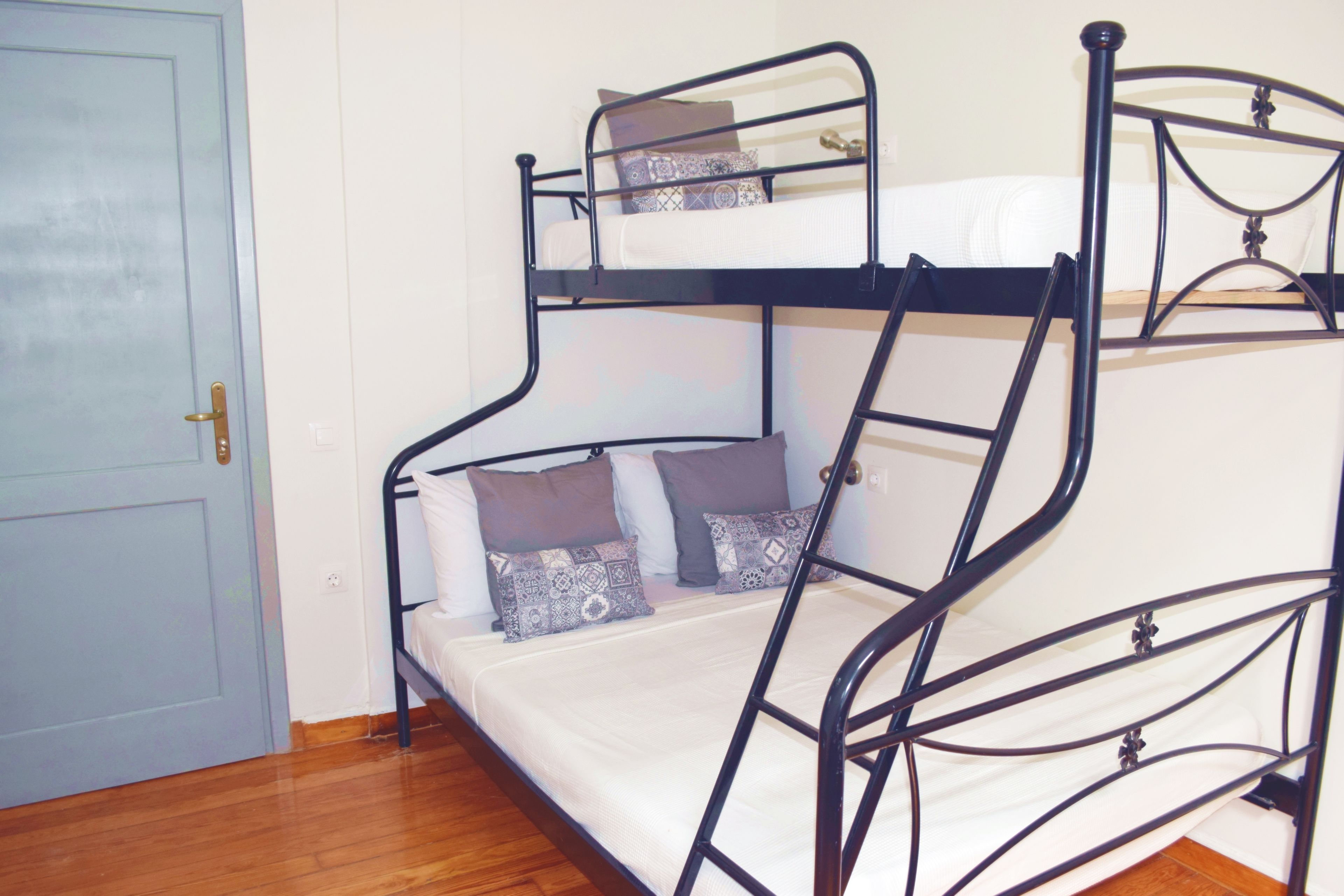 A bunk bed with a ladder, a door, and patterned pillows.