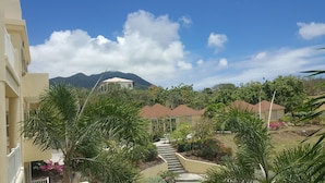A residential area with a staircase leading to a house with a brown roof, surrounded by greenery and a mountain in the background. - Sea Dreamer Villa 10E Hamilton Beach Villas and Spa -2BRD (Charlestown)