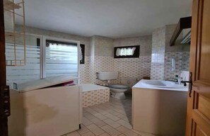 Une petite salle de bain comprenant des toilettes, un lavabo et une fenêtre.