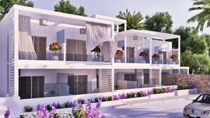 A modern two-story building with balconies, large windows, and a stone wall. - Kellys Plus (Rhodes)