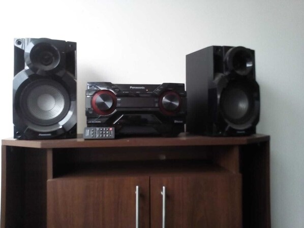 A wooden cabinet with two large speakers on top and a smaller electronic device in the center.