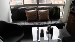 Et moderne opholdsrum med en sort lædersofa, et glasbord og en sort stol.