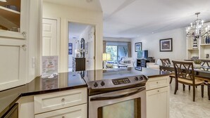 Een moderne keuken met een grote kookplaat, witte kastjes en een eethoek met een kroonluchter.
