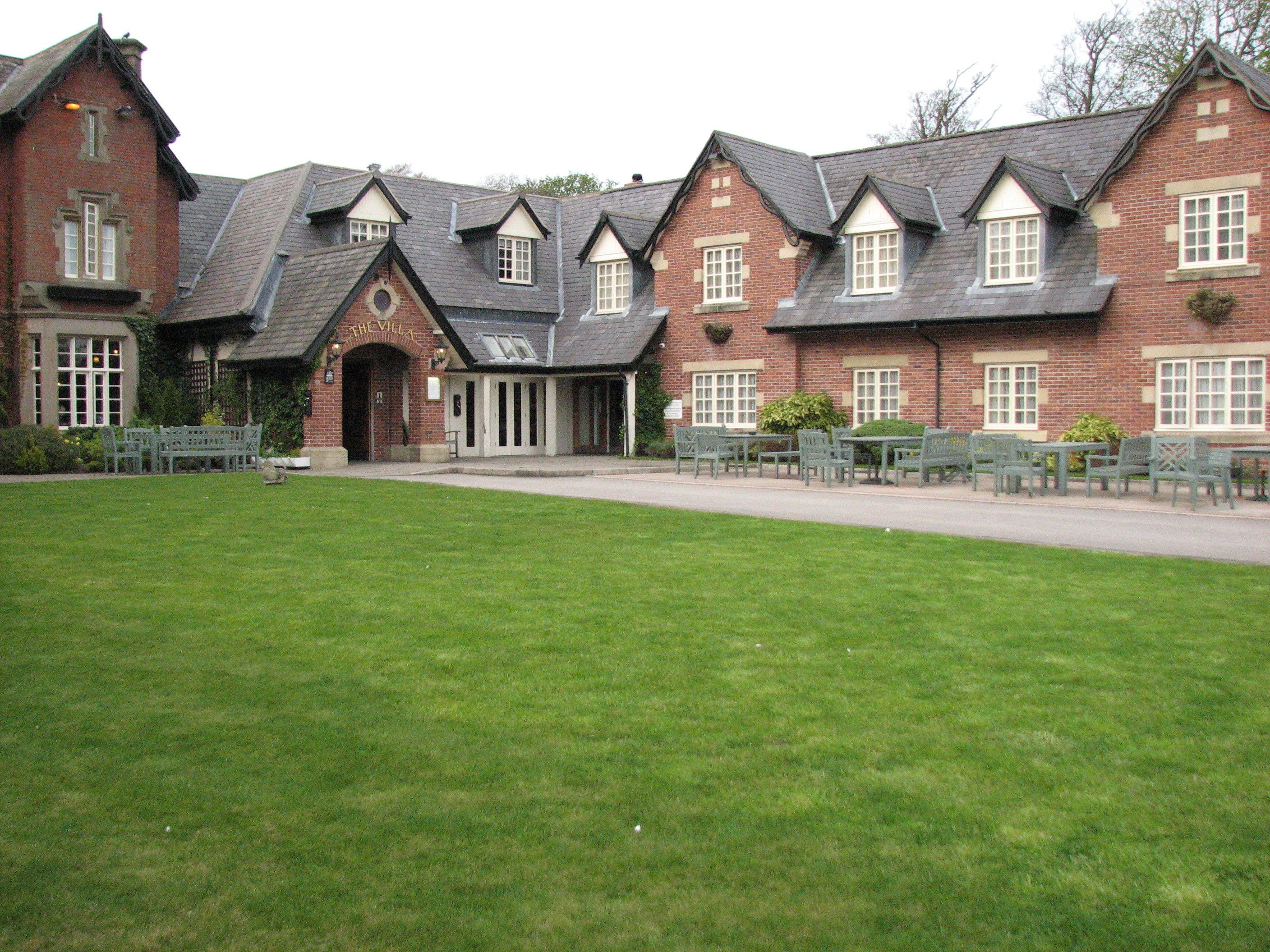 A traditional brick building with a symmetrical facade, multiple windows, and a central entrance.