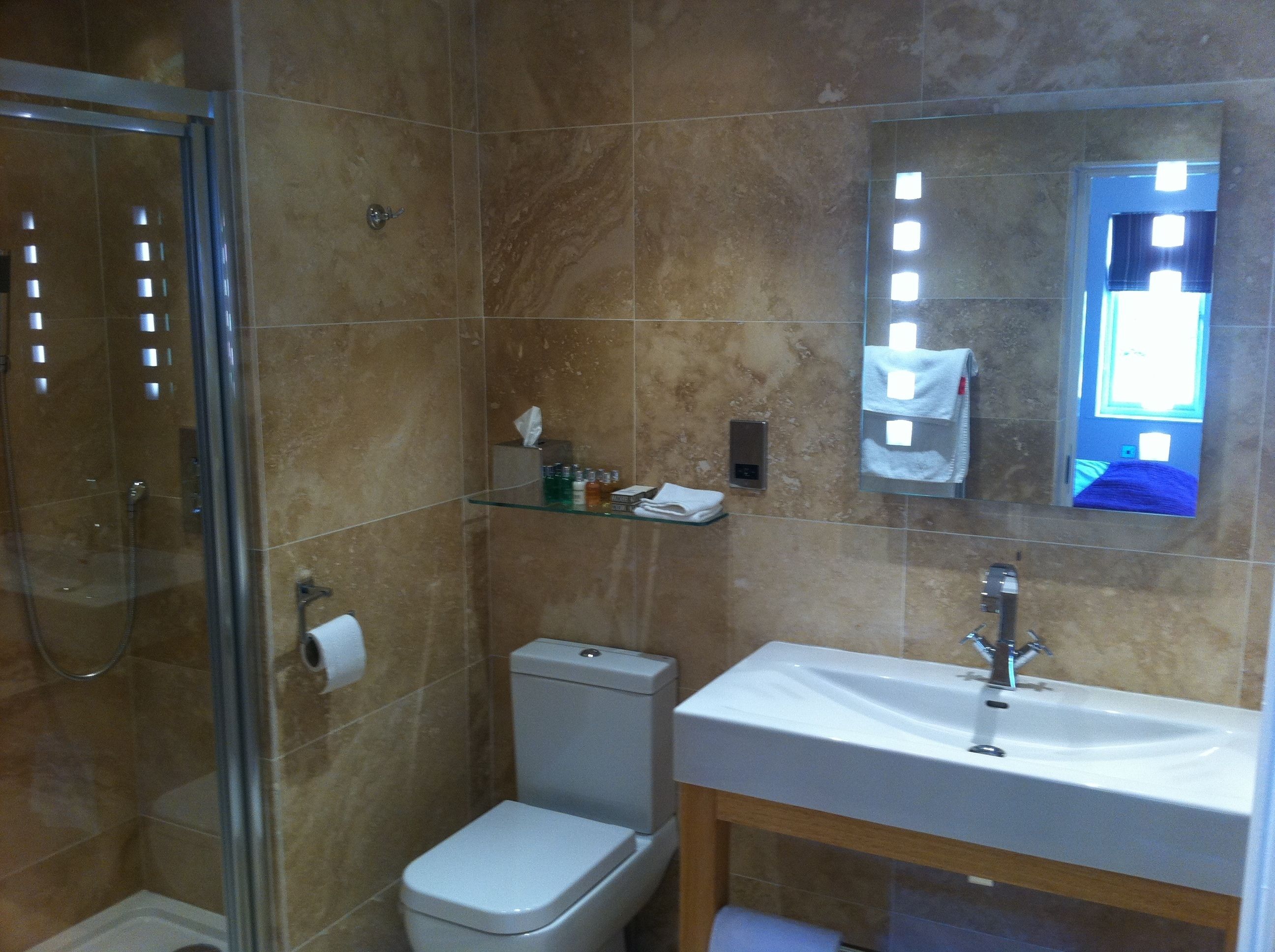 Un baño con cabina de ducha de vidrio, inodoro, lavabo y espejo.
