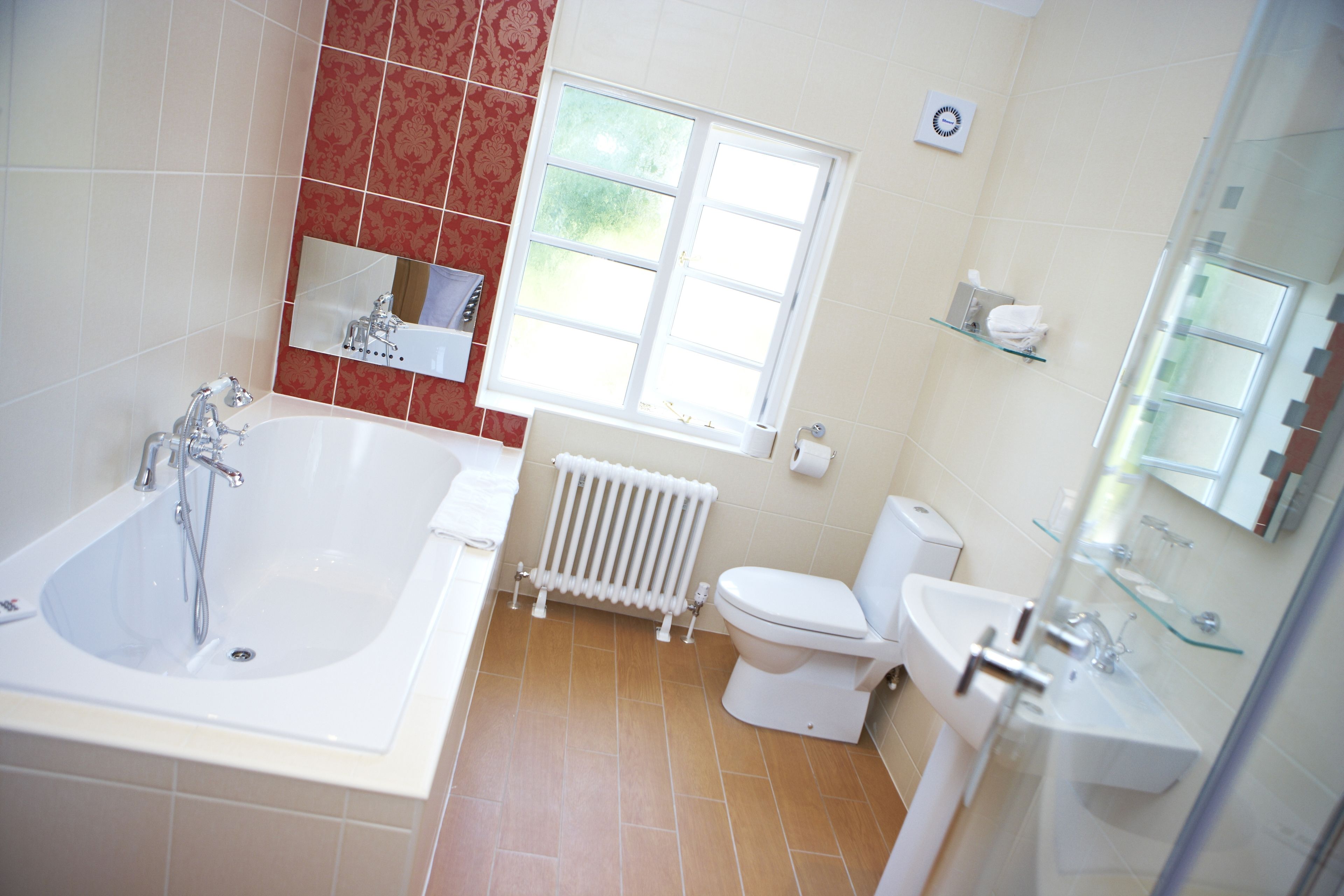 A bathroom with a bathtub, toilet, sink, and a window providing natural light.