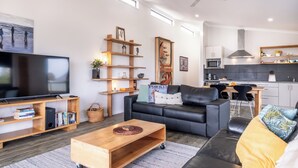 Ein modernes Wohnzimmer mit einer Couch, einem Couchtisch, einem Fernseher und Bücherregalen.