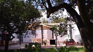 Un patio con un espacio de descanso cubierto, una pequeña mesa y plantas en macetas.
