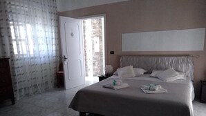 Un dormitorio con una cama grande, una puerta que da a un balcón y vistas al exterior.