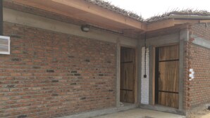 A brick building with two wooden doors, a concrete step leading to the entrance, and a small overhang above the doorways. - Summer Cottage (Arugam Bay)