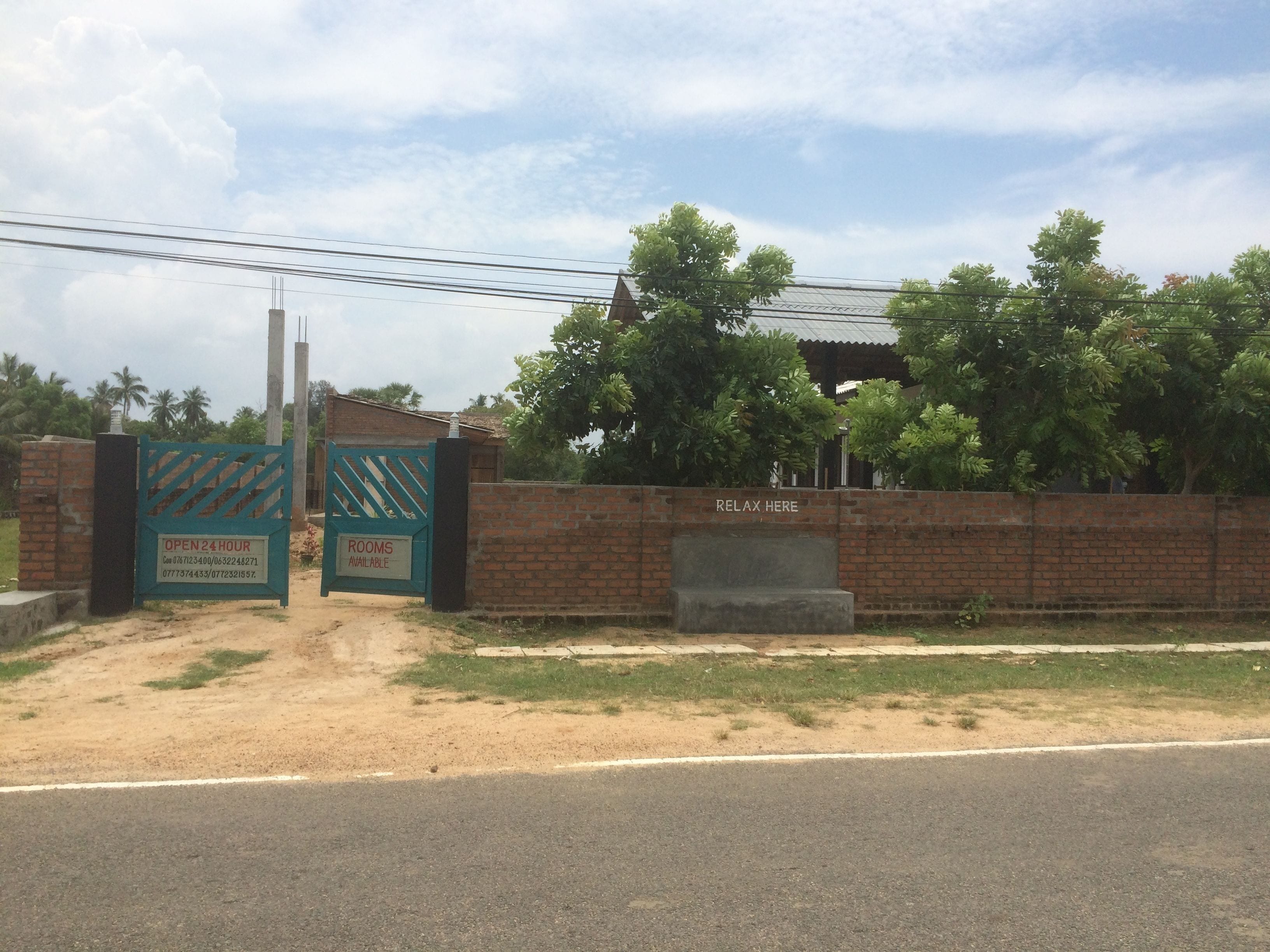 A gated entrance with a sign indicating 24-hour availability and contact numbers.
